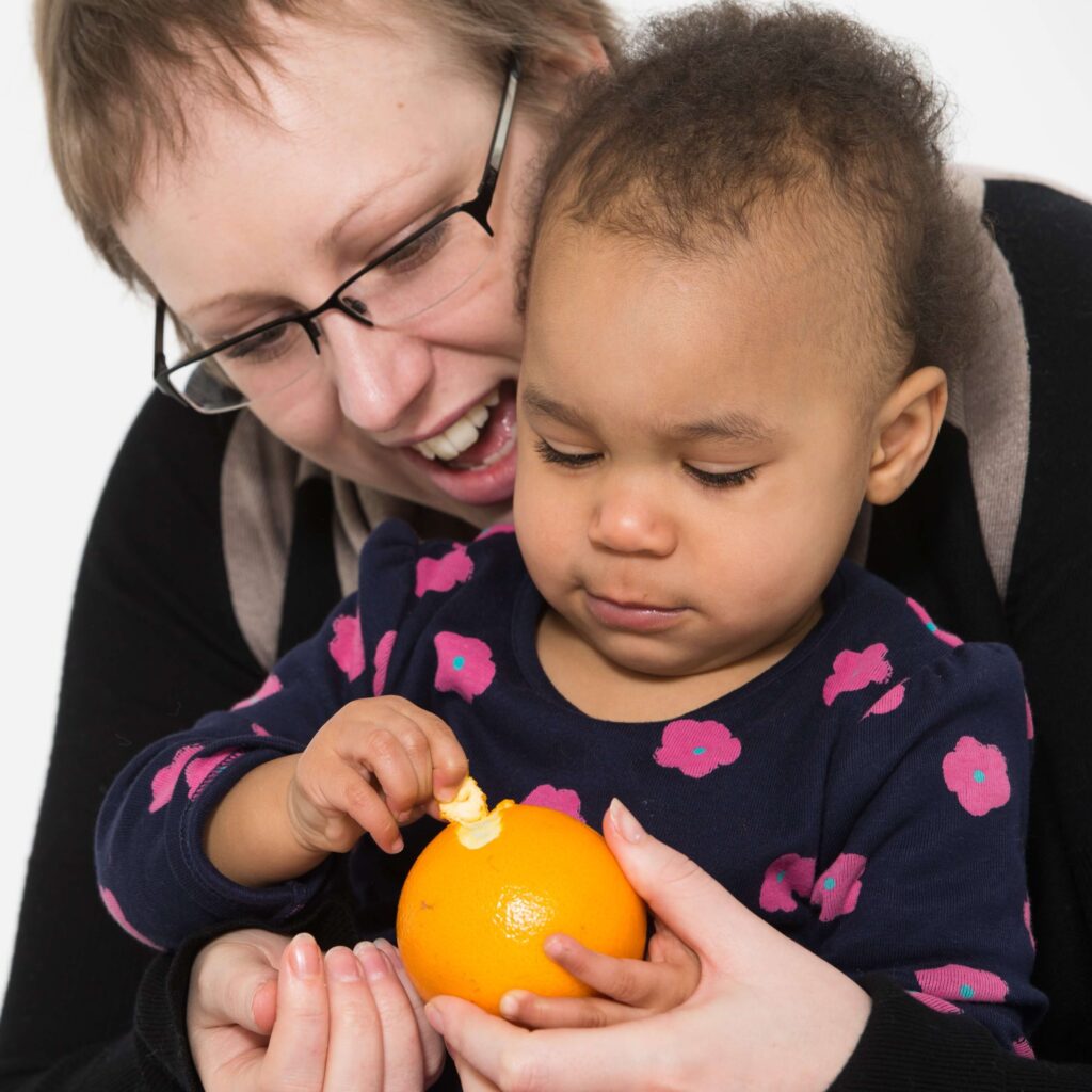 Mum and toddler peeling orange together