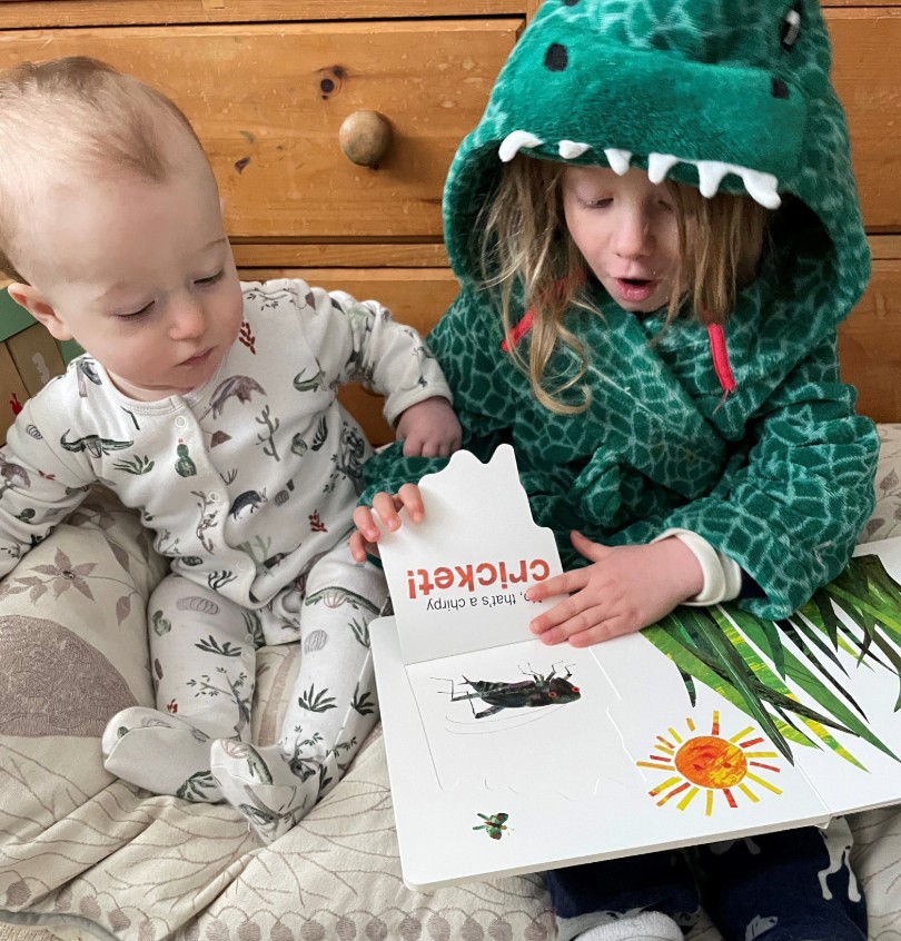 Big sister reading Imagination Library book to baby